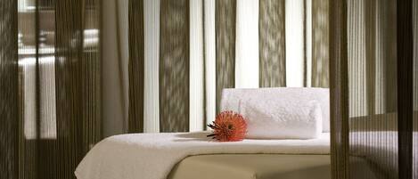 A modern hotel room with a bed, a small table, and a chair.