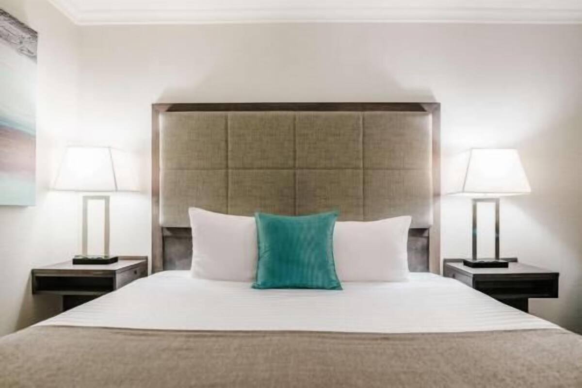 A hotel room with a large bed, two bedside tables, and a headboard.