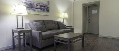 A modern living room with a grey sofa, two side tables with lamps, and a wooden coffee table.