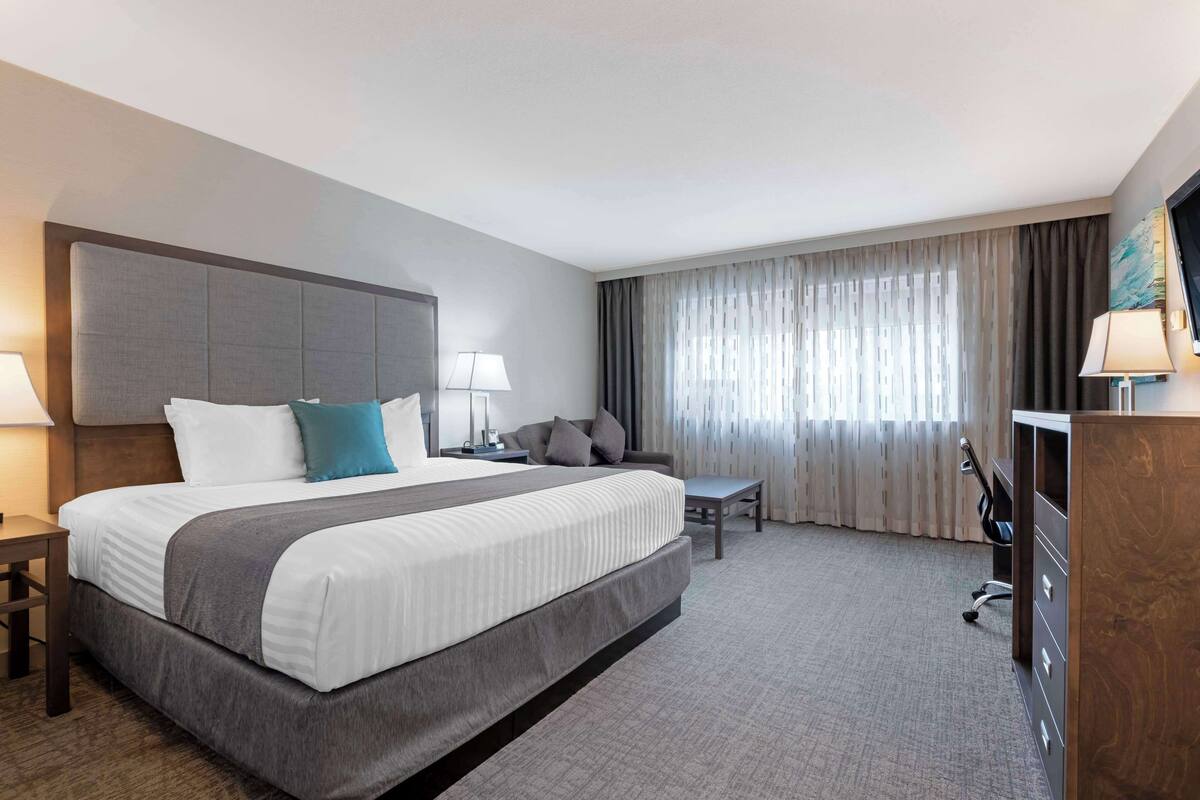 Habitación de hotel con una cama grande, un escritorio, una silla y un televisor.