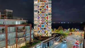 Een modern hoog gebouw met een kleurrijke gevel, meerdere balkons en uitzicht op de waterkant.