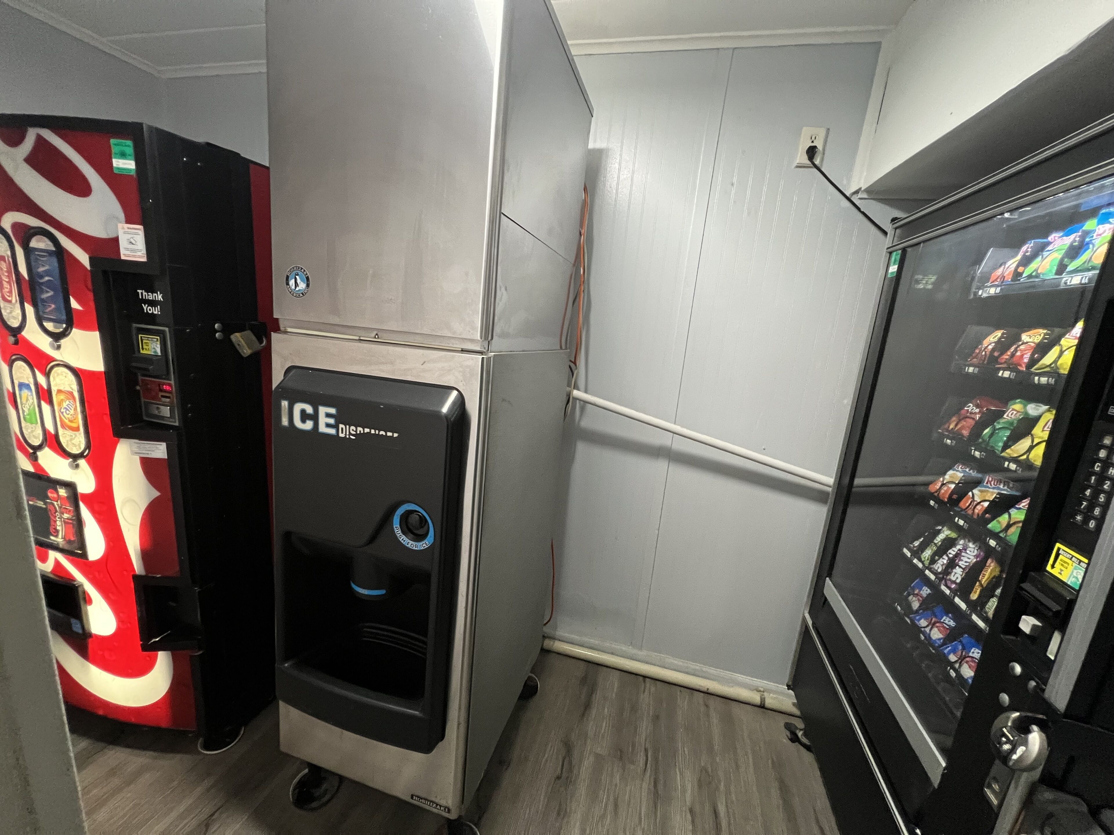 A vending machine area with a Coca-Cola branded machine, an ICE dispenser, and a snack vending machine.