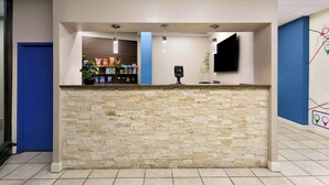 A reception area with a stone counter, a blue door, and a wall-mounted TV. - Travelodge by Wyndham Aberdeen (Aberdeen)