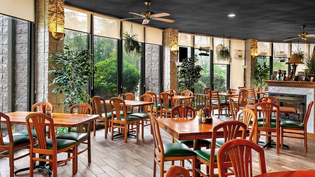 A restaurant with wooden tables and chairs, large windows, and a fireplace. - Travelodge by Wyndham Aberdeen (Aberdeen)