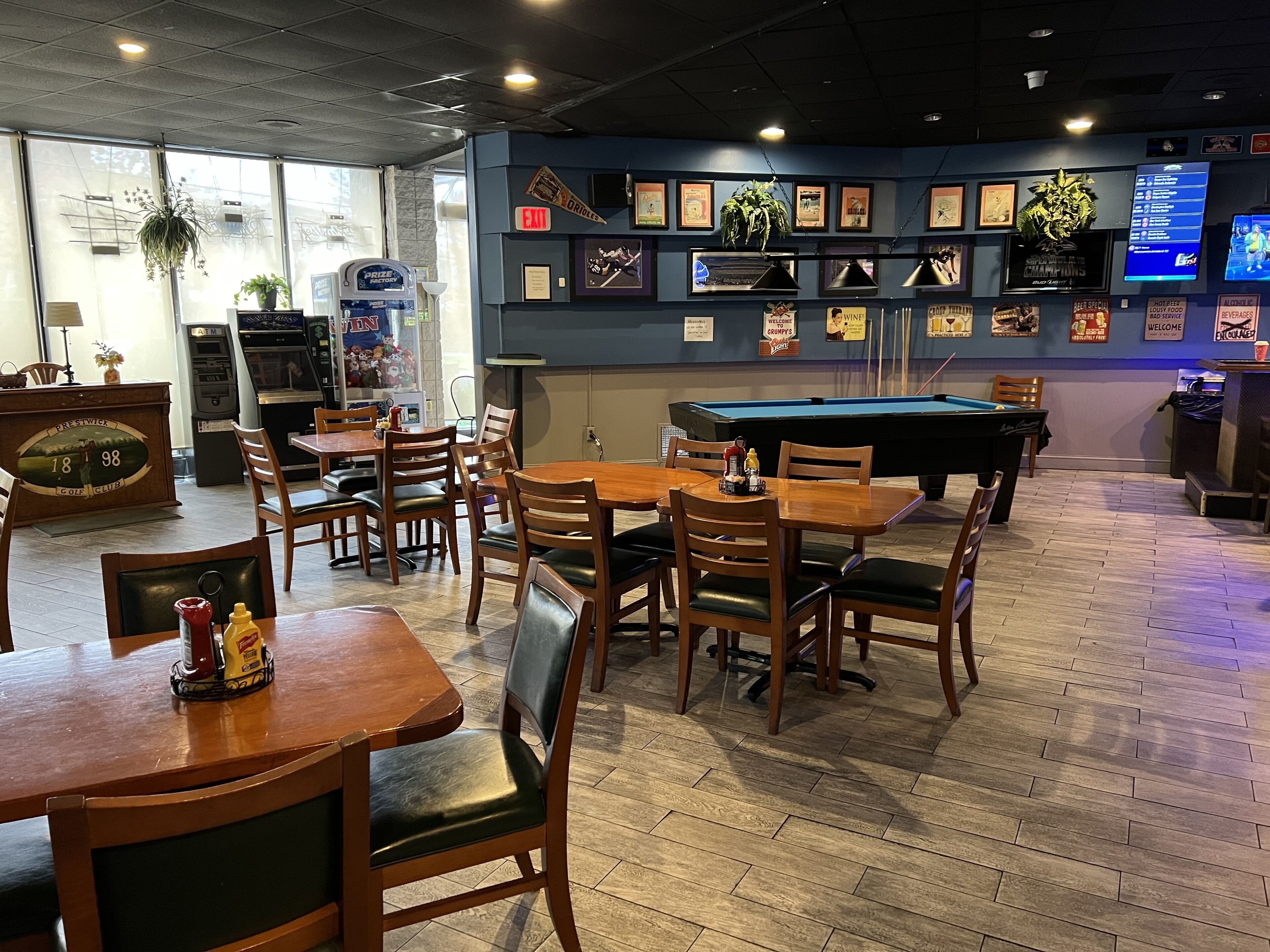 A restaurant with wooden tables and chairs, a pool table, and various framed pictures on the walls.