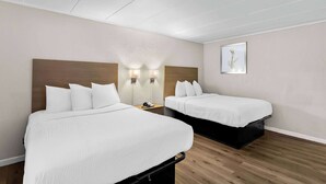 A hotel room with two beds, a wooden headboard, a nightstand with a phone, and a framed picture on the wall. - Travelodge by Wyndham Aberdeen (Aberdeen)