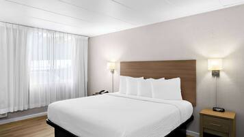A neatly made bed with white linens, a wooden headboard, and two bedside lamps.