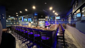 A bar area with a long counter, multiple TVs, and a variety of bottles. - Travelodge by Wyndham Aberdeen (Aberdeen)
