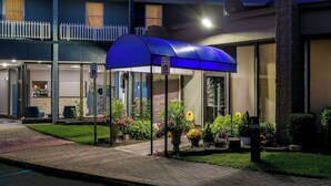 A hotel entrance with a covered waiting area, a visible entrance, and a small garden with potted plants. - Travelodge by Wyndham Aberdeen (Aberdeen)