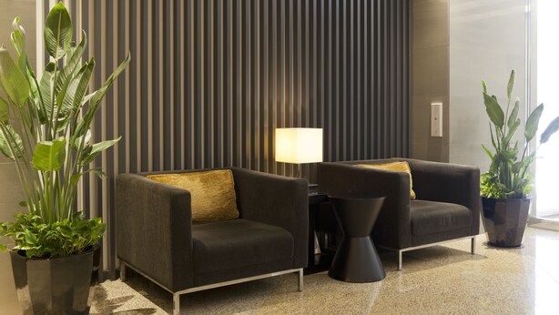 Un hall d’entrée moderne avec deux canapés, une lampe sur pied et des plantes en pot.