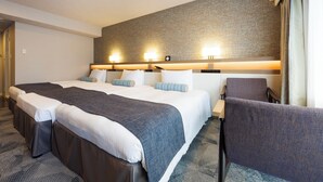 Une chambre d’hôtel avec un grand lit, deux tables de chevet, une chaise et un mur décoré d’un motif en briques.