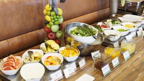 Une table de buffet garnie de divers plats et un grand vase rempli de fruits.