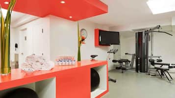 Un vestíbulo moderno de hotel con una recepción, un reloj, un televisor y un área de gimnasio.