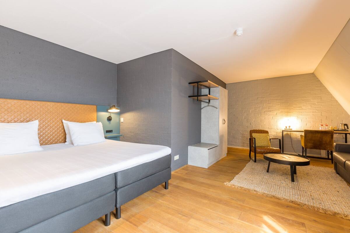 A modern bedroom with a large bed, a desk, and a chair.