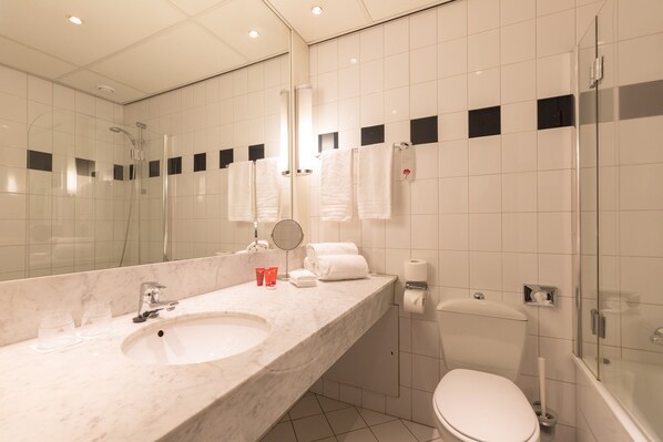 A modern bathroom with a marble sink, a glass-enclosed shower, a toilet, and a large mirror.