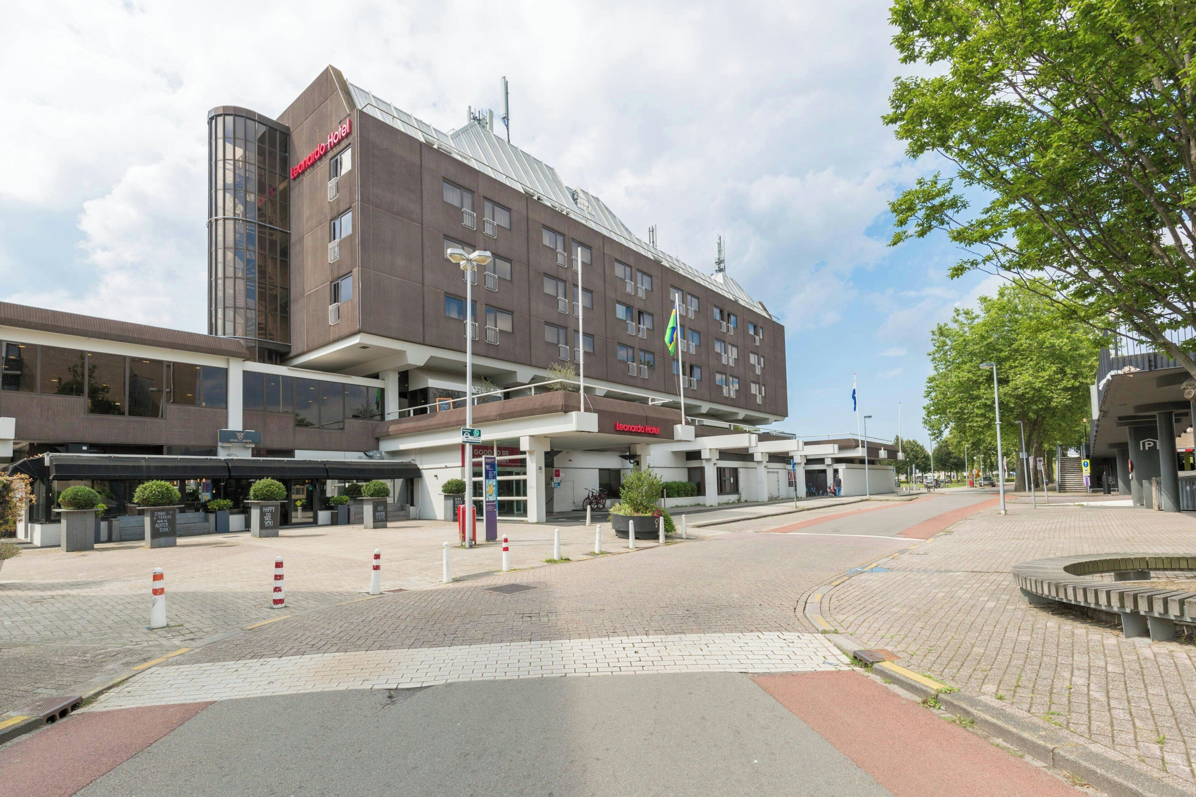 Ein modernes Hotel mit auffälligem Eingang, einem überdachten Gang und einer Flagge.