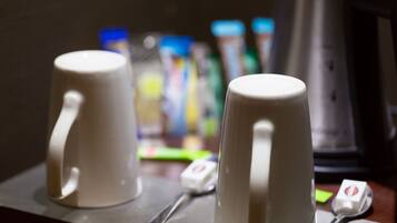 Two white ceramic mugs on a tray with a spoon and a small container, likely a tea bag, in a dimly lit setting.