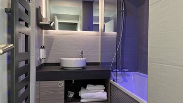 A modern bathroom with a built-in sink, a mirror, a shower, and a towel rack.