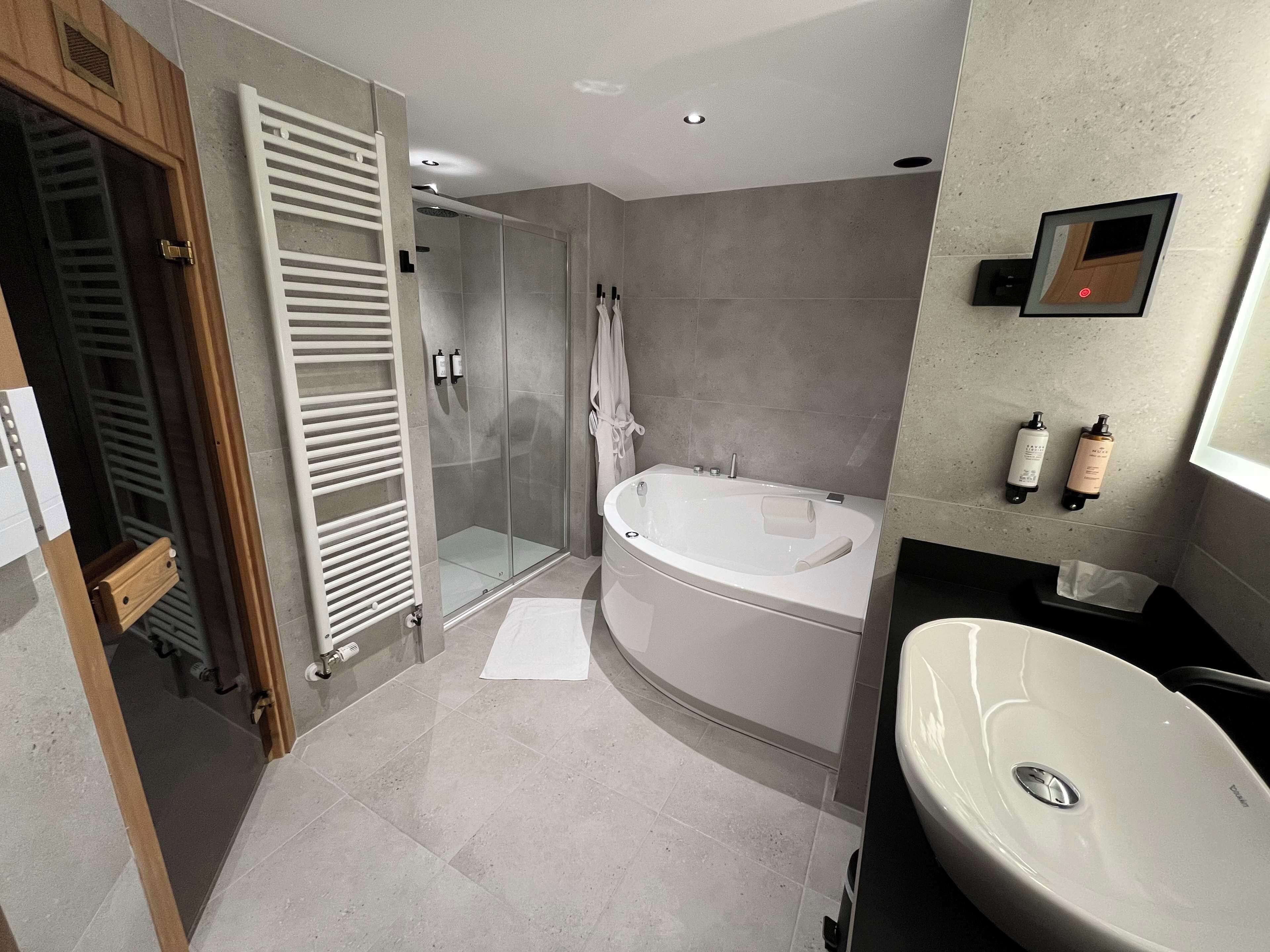 Une salle de bain moderne dotée d’une douche à l’italienne, d’une baignoire sur pieds et d’un lavabo.