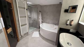 Une salle de bain moderne dotée d’une douche à l’italienne, d’une baignoire sur pieds et d’un lavabo.