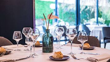 Una mesa de comedor con copas de vino, un florero con flores y platos con pasteles.