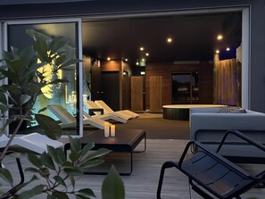 Un espace de d étente intérieur moderne, doté de fauteuils confortables, d’un jacuzzi et d’une cloison en verre agrémentée d’une plante.