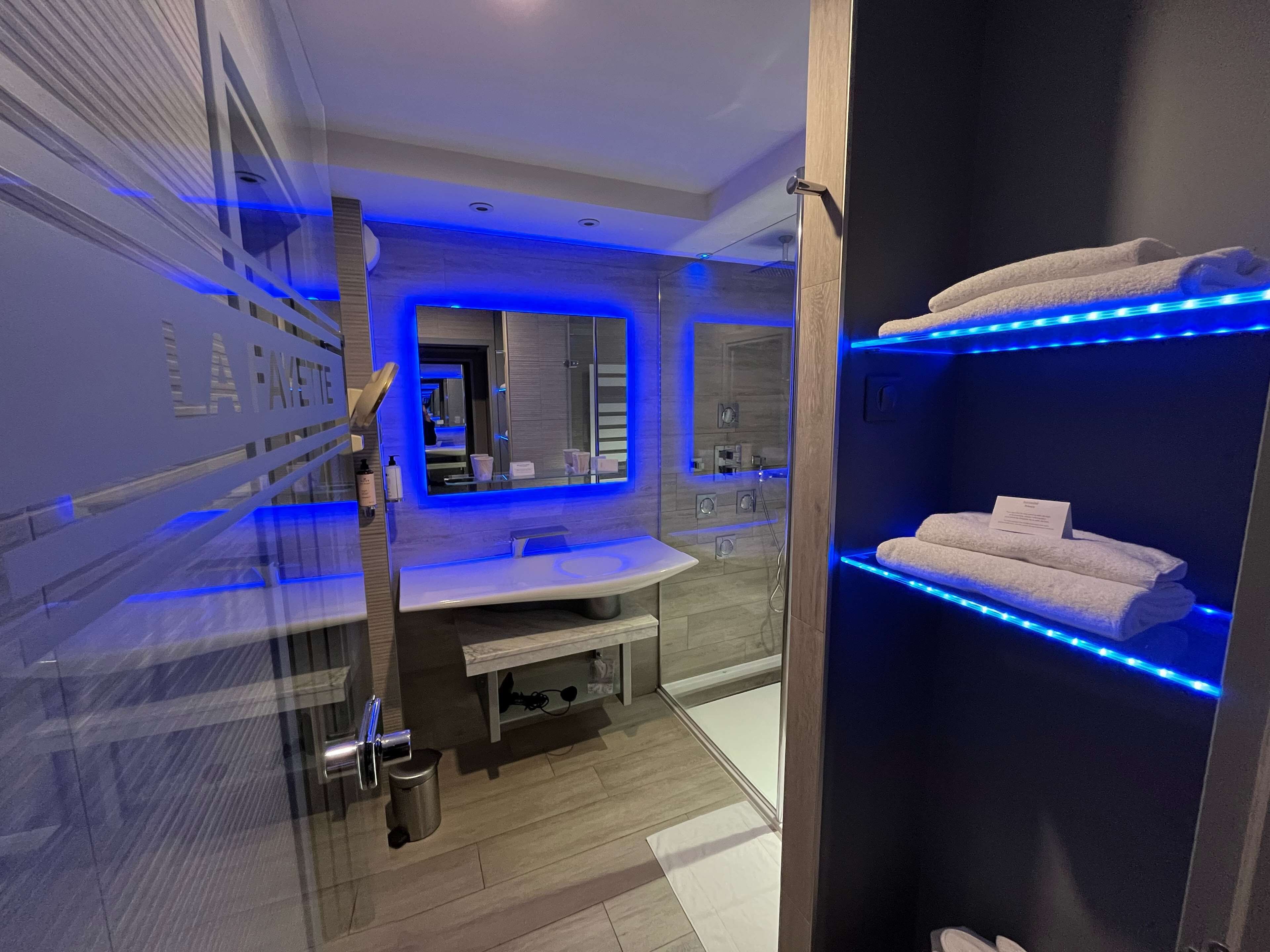 A modern bathroom with a glass shower enclosure, a vanity with a mirror, and a towel rack.