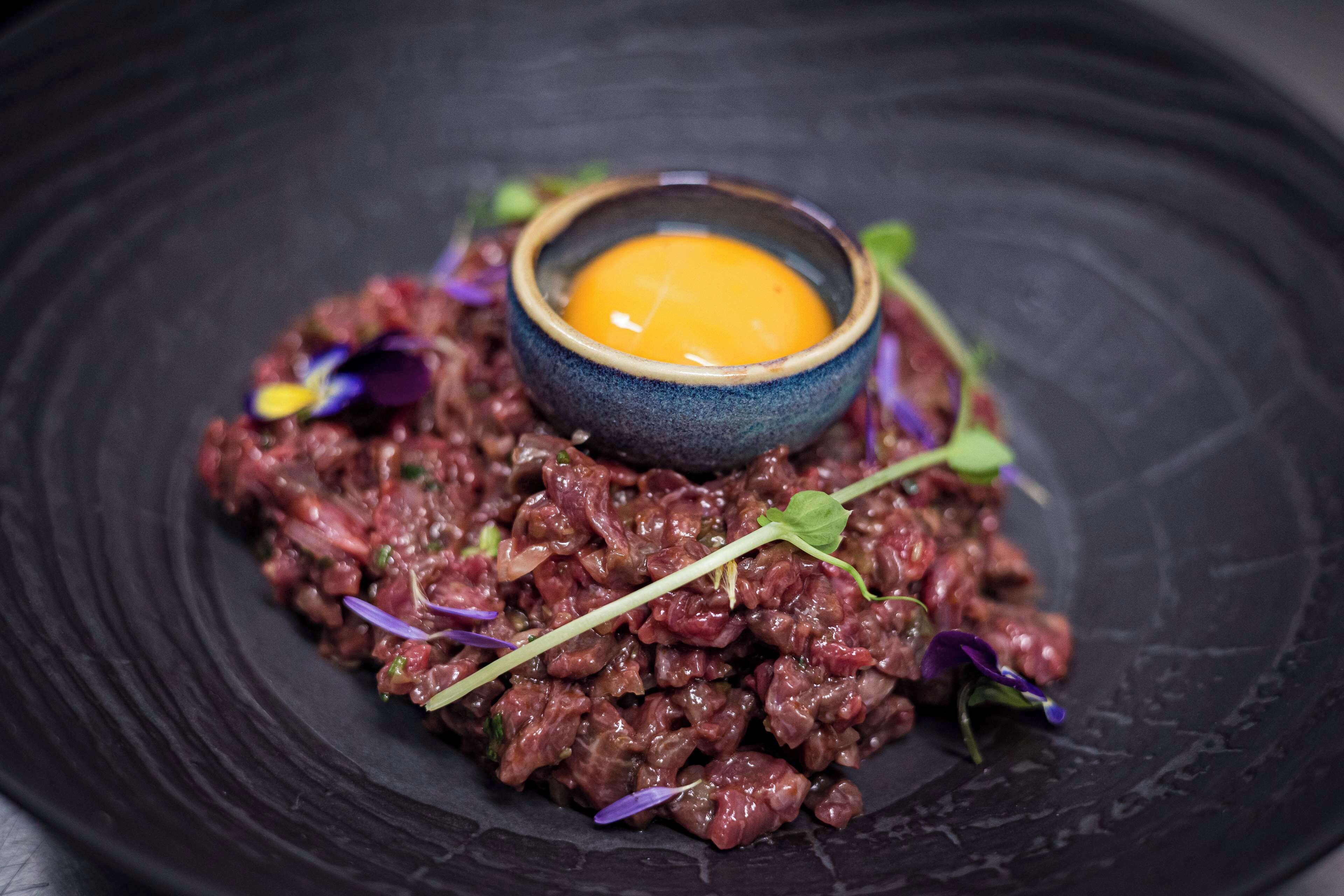 A dish with a bowl of sauce on a plate.