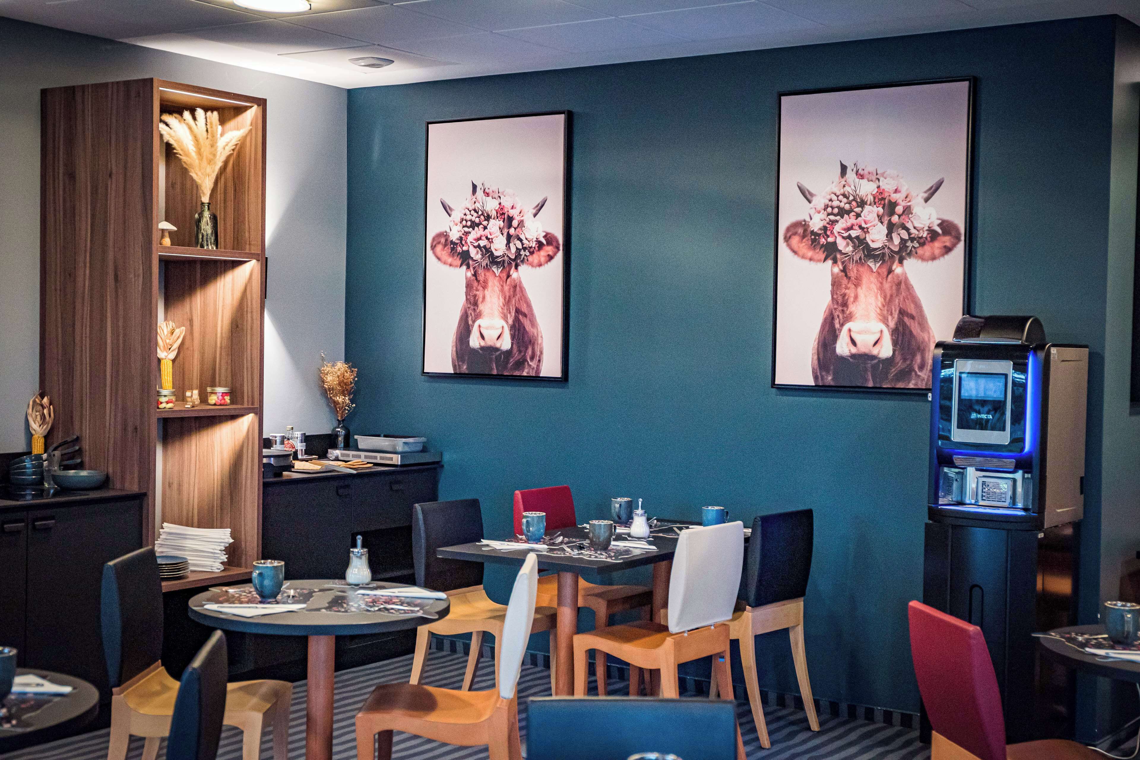 Une chambre d’hôtel avec un coin repas, une télévision et des œuvres d’art accrochées au mur.