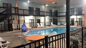 An indoor swimming pool with a covered area, multiple lounge chairs, and a staircase leading to an upper level. - Hutchi Bell (Hutchinson)