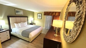 A hotel room with a bed, bedside tables, a mirror, and a dresser. - Hutchi Bell (Hutchinson)