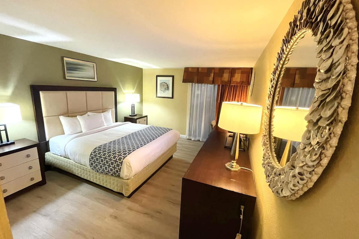 Une chambre d’hôtel comprenant un lit, des tables de chevet, un miroir et une commode.