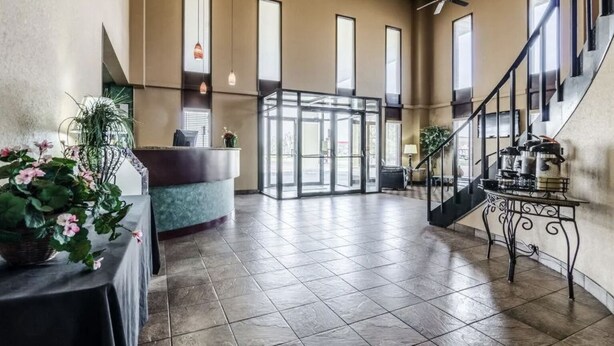 A spacious lobby with a reception desk, a staircase, and a large glass door leading outside. - Hutchi Bell (Hutchinson)