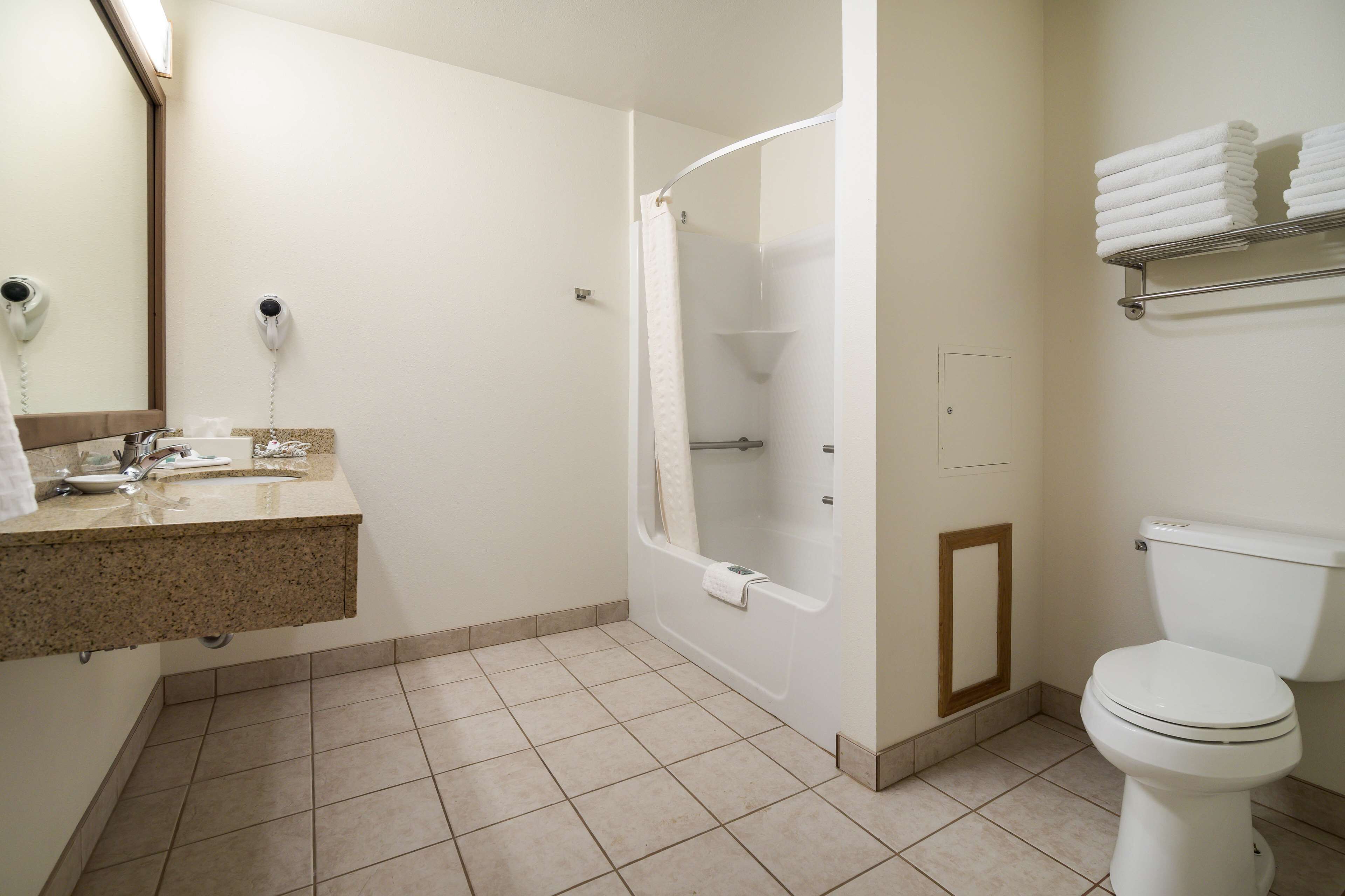 A bathroom with a sink, mirror, shower, toilet, and towel rack.