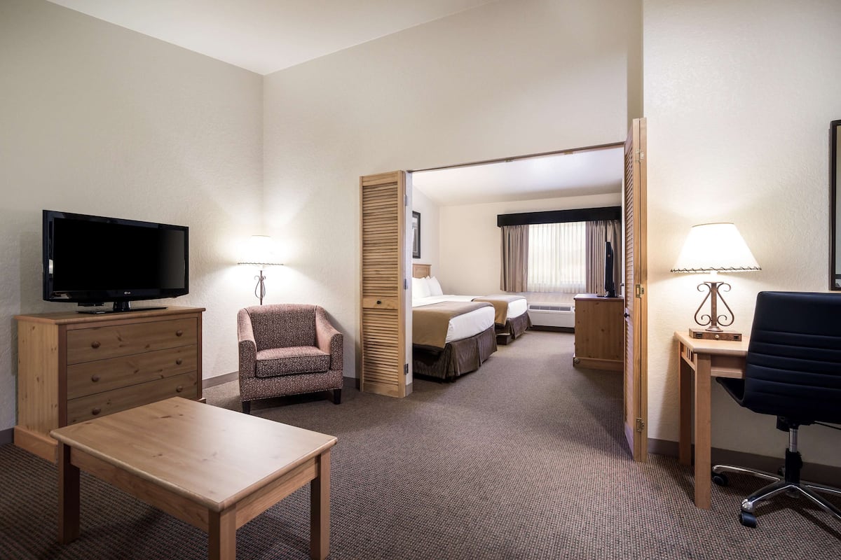 Une chambre d’hôtel équipée d’une télévision, d’un bureau avec une lampe, d’une chaise, d’un lit et d’une armoire.