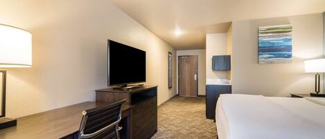 A hotel room with a bed, a desk with a chair, a television, and a painting on the wall.