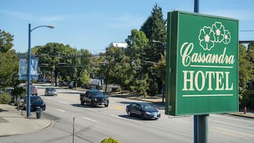 Un panneau vert indiquant l’hôtel Cassandra, offrant une vue dégagée sur la rue et les voitures garées.