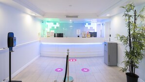 A reception area with a reception desk, a security checkpoint, and a potted plant. - Cassandra Hotel (Vancouver)