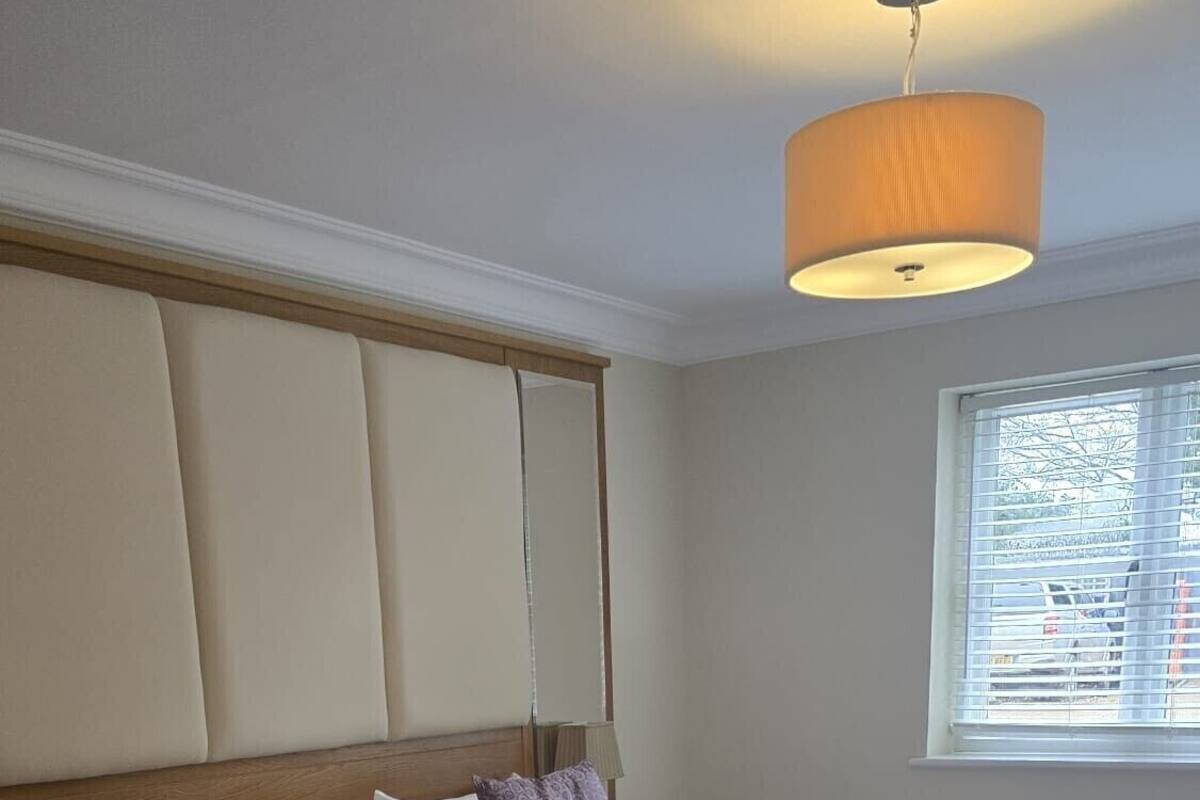 A hotel room with two beds, a window with blinds, a lamp, and a chair.