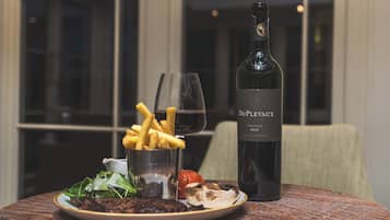 Un plato de comida que incluye papas fritas, una copa de vino y una botella de vino Duplevaux sobre una mesa.