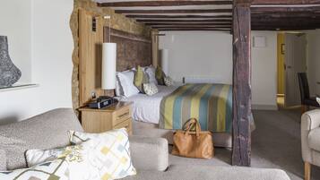 A bedroom with a bed, bedside table, lamp, and a handbag on the floor.