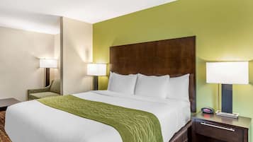 Een hotelkamer met een groot bed, twee nachtkastjes met lampen, een stoel en een groene wand.