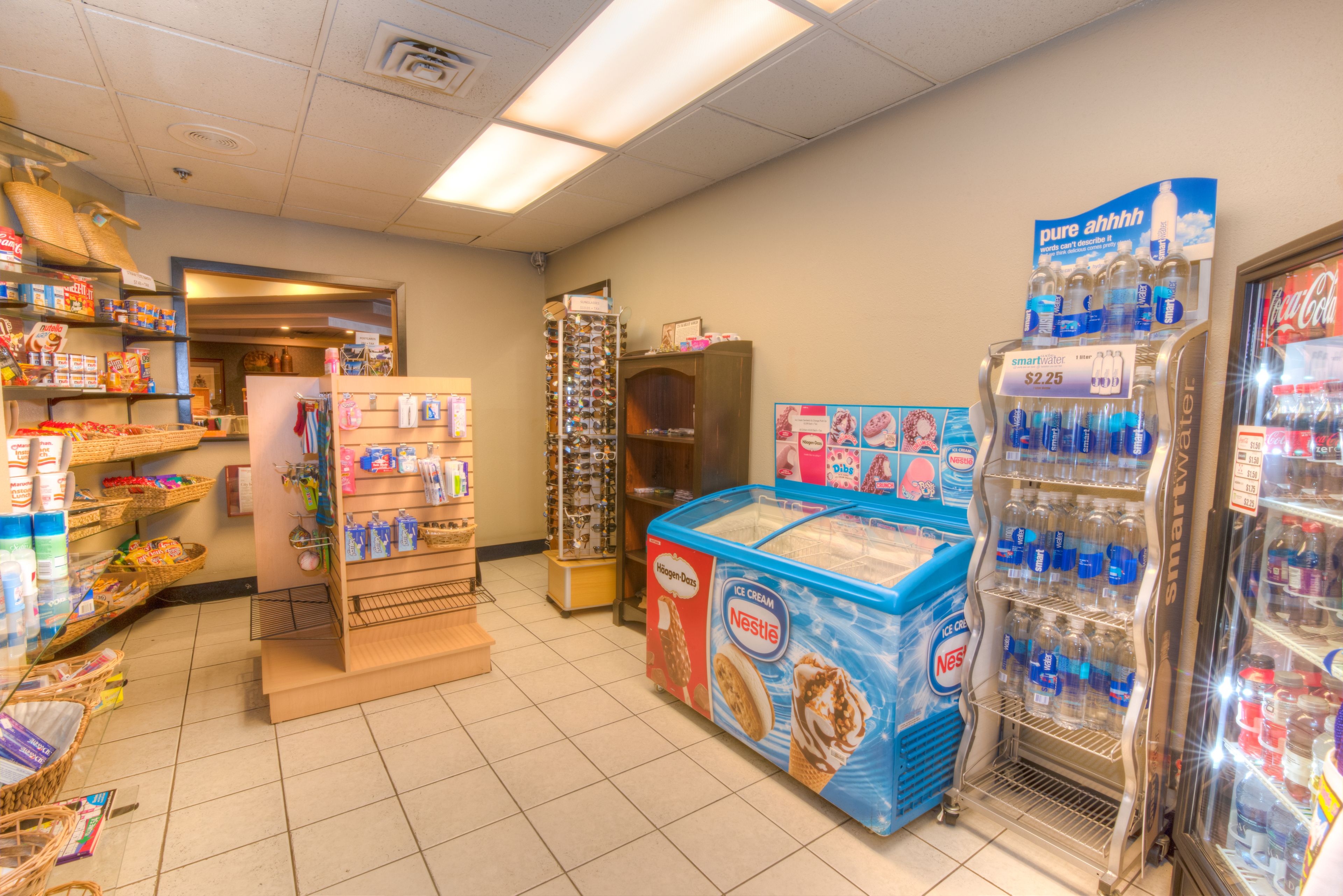 A grocery store interior with shelves stocked with various products, a display of Nestle ice cream, and a refrigerated section.
