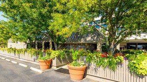 A building with a stone facade and a wooden fence adorned with colorful flowers. - Grand Vista Hotel (Grand Junction)