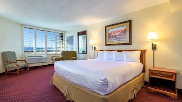 Habitación de hotel con una cama grande, dos sillas, un escritorio y una ventana con vistas.