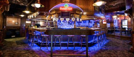 A bar area with a wooden ceiling, a Budweiser sign, and multiple bar stools.