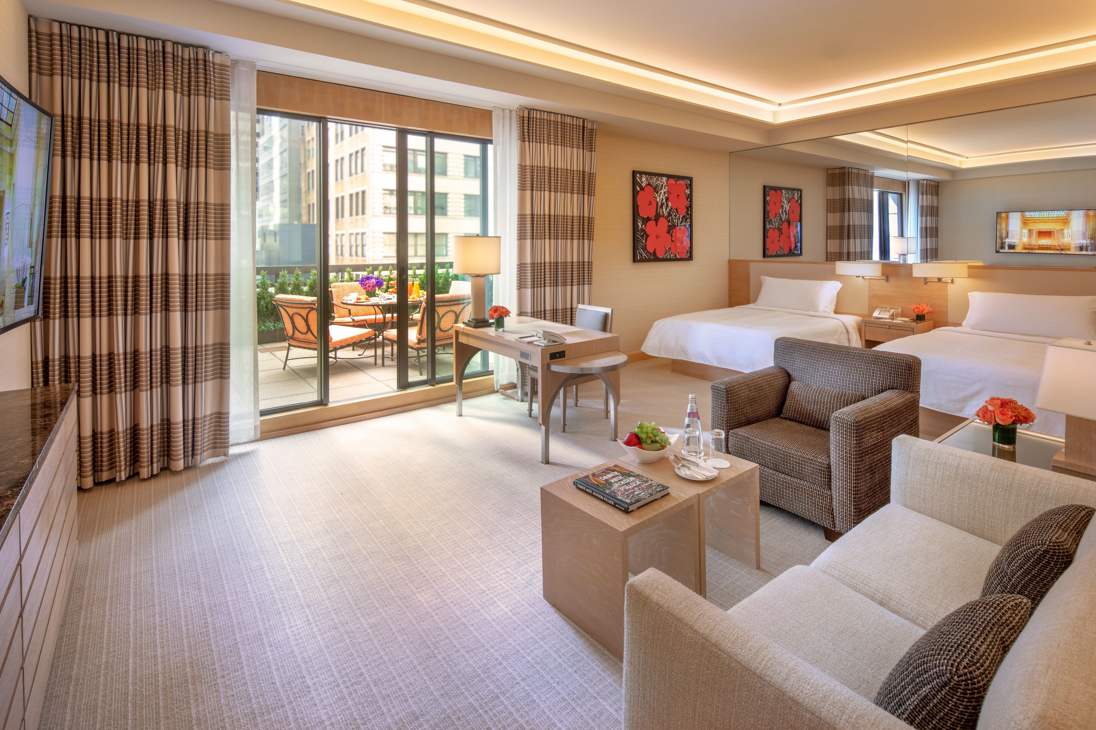 Una habitación de hotel con balcón, una cama, un sofá, un escritorio y una silla.