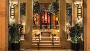 Eine Lobby mit einer monumentalen Treppe, einem Empfangsbereich und großen Kübelpflanzen.