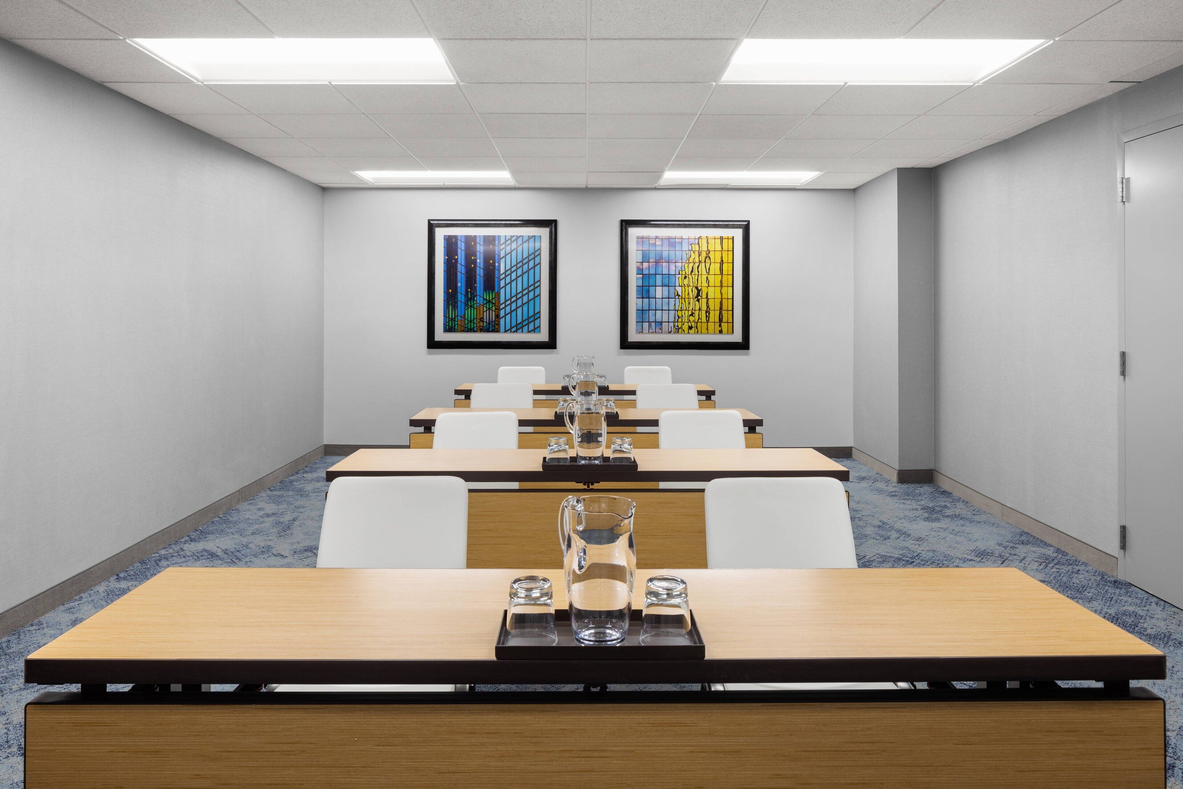A conference room with a long table, chairs, and two framed artworks on the walls.