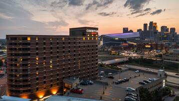 A multi-story hotel with a prominent Courtyard Marriott sign, surrounded by a parking lot and a city skyline in the background.